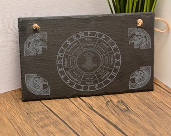 May include: A rectangular black slate serving board with a Norse mythology design. The board features a central circular design with runes and a hammer symbol, surrounded by corner carvings of ravens. It has a rope handle.