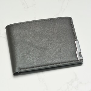 May include: A gray leather wallet with a silver metal accent.