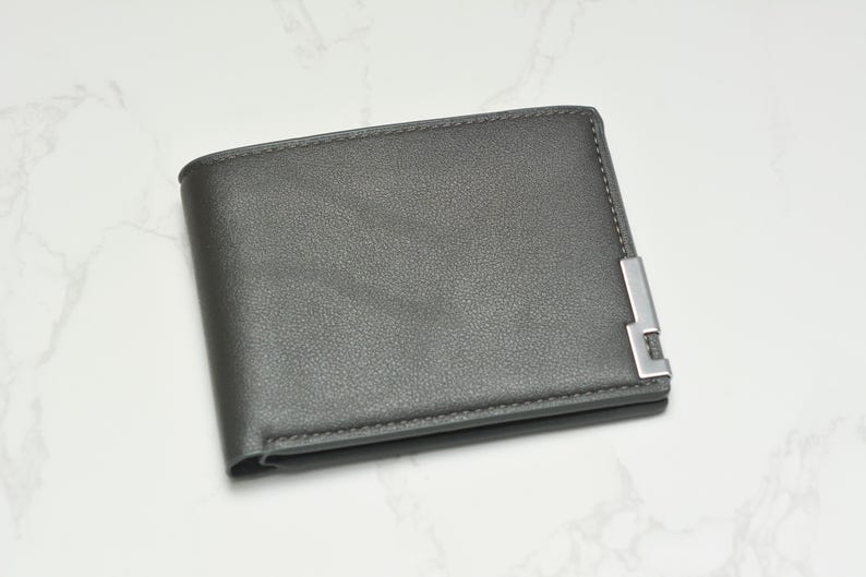 May include: A gray leather wallet with a silver metal accent.