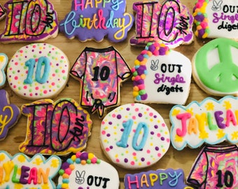 May include: Assortment of decorated sugar cookies with colorful frosting. Some cookies feature the number "10" in blue, others say "Happy Birthday" and "Jaylean". Several cookies have a tie-dye design.