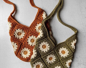 Könnte beinhalten: Zwei gehäkelte Taschen mit Gänseblümchen-Mustern. Eine Tasche ist braun und die andere grün.