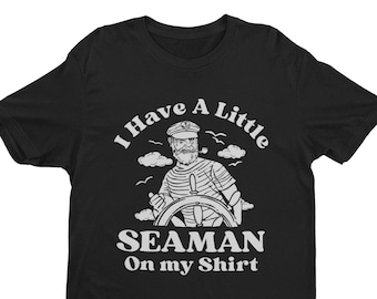 May include: Black t-shirt with a white graphic of a cartoon sailor at the helm of a ship. The text "I Have A Little Seaman On My Shirt" is printed below the image.