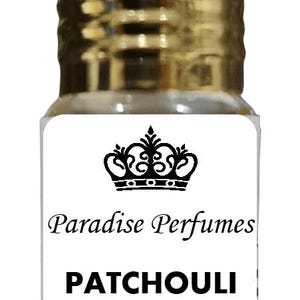 Puede incluir: Una botella dorada con una etiqueta blanca que dice "Paradise Perfumes Patchouli Oud Perfume Oil". Una corona negra está en la parte superior de la etiqueta.