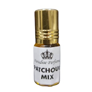 Könnte beinhalten: Eine kleine, durchsichtige Glasflasche mit einem goldenen Verschluss und einem weißen Etikett. Das Etikett zeigt ein Kronendesign und den Text "Paradise Perfums PATCHOU MIX".