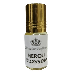 May include: A small perfume bottle with a gold cap and a white label. The label features a crown design and the words "Paradise Perfume" above "Neroli Blossom". The bottle contains a light yellow liquid.