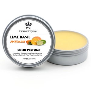 Puede incluir: Una lata de plata con tapa amarilla que contiene un perfume sólido. La etiqueta dice "PPG Paradise Perfumes Lime Basil Mandarin Solid Perfume" y enumera los ingredientes: Cera de abejas, manteca de karité, aceite de almendras, perfume, pachulí, aceites esenciales de ylang-ylang. La etiqueta también dice "Handmade in UK".