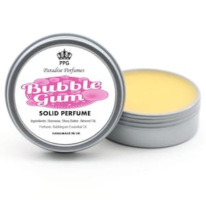 Puede incluir: Una lata plateada de perfume sólido con el texto "Bubble Gum" en rosa y blanco. La lata abierta revela un bálsamo amarillo. La etiqueta también incluye "Paradise Perfumes" y "HANDMADE IN UK".