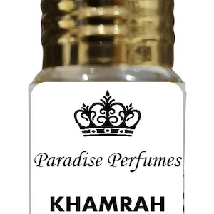 May include: A small clear glass bottle of perfume oil with a metallic gold cap. The white label features a black crown icon above the text Paradise Perfumes, the word KHAMRAH in bold black letters, and the words Perfume Oil at the bottom.