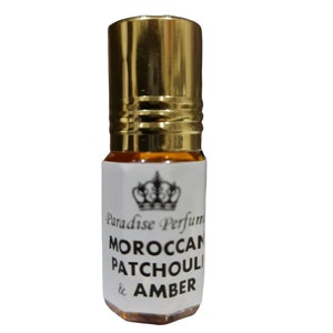May include: A small, clear glass bottle with a gold cap and a white label. The label features a crown design and the text "Paradise Perfume Moroccan Patchouli & Amber".