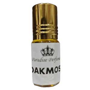 Puede incluir: Una pequeña botella de vidrio transparente con una tapa dorada y una etiqueta blanca. La etiqueta tiene un diseño de corona y el texto "Paradise Perfume" y "OAKMOS".