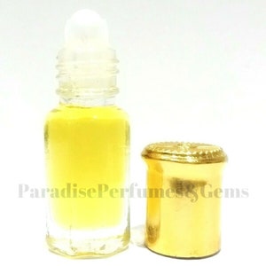 May include: A clear glass bottle with a gold cap and a rollerball applicator. The bottle is filled with a yellow liquid. The bottle is labelled "Paradise Perfumes & Gems".