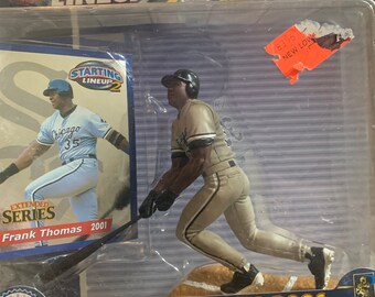 Pode incluir: Um pacote de plástico contendo uma figura de beisebol de Frank Thomas, um jogador do Chicago White Sox, em posição de rebatida. O pacote é azul e branco com o texto "Extended Series 2001 Frank Thomas Chicago White Sox" impresso nele.
