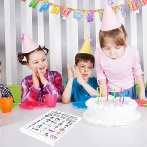 May include: A group of children at a birthday party. A white cake with lit candles sits on a table. A game board with the text "Hunters Queen Bingo" is in the foreground. Children wear party hats and celebrate.