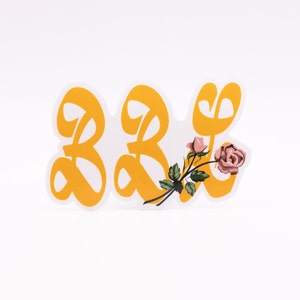 May include: A yellow sticker with the number "33" in a stylized font. A pink rose with green leaves is attached to the right side of the sticker.
