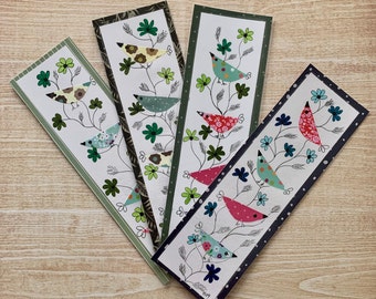 May include: Four colorful bookmarks with a floral design and birds. Each bookmark features a different bird with a unique pattern and color scheme. The birds are surrounded by green leaves and flowers.