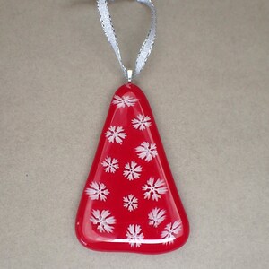 May include: A red glass Christmas tree ornament with white snowflake designs.