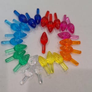 May include: Assortment of 20 clear plastic Christmas light bulb covers in various colors, including red, orange, yellow, green, blue, and pink. The covers are arranged in a circle on a white surface.