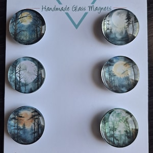May include: Six round glass magnets with a woodland scene and a full moon. The magnets are arranged in two rows of three. The magnets are handmade and feature a variety of moon phases and forest scenes. The text "Cabochon Design Studio" is printed on the bottom of the card.