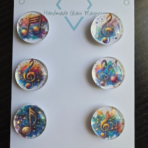 May include: Six round glass magnets with colorful watercolor backgrounds and gold musical notes. The magnets are arranged in two rows of three on a white card with the text "Cabochon Design Studio Handmade Glass Magnets".