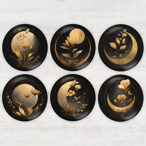 May include: Six black decorative plates with gold floral and moon designs. Each plate features a different arrangement of gold flowers, leaves, and a crescent moon or full moon against a dark background. The plates are round.