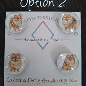 May include: Set of four round glass magnets featuring a watercolor illustration of a Pomeranian dog. The magnets are white with a clear glass dome and are displayed on a white card with the text "CabochonDesignStudio.etsy.com" and "Handmade Glass Magnets".