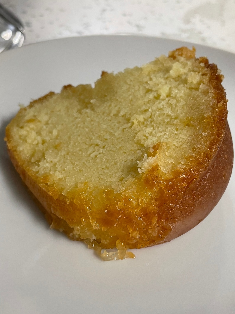 May include: A slice of yellow cake with a glazed, golden brown exterior. The cake is moist and has a crumbly texture.