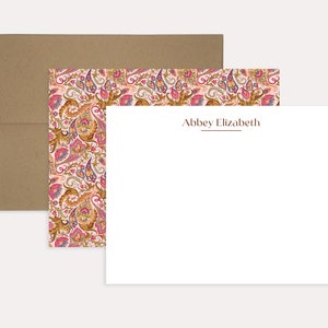 May include: A white card with a pink and gold paisley pattern border. The card has the name "Abbey Elizabeth" printed in brown text at the top.