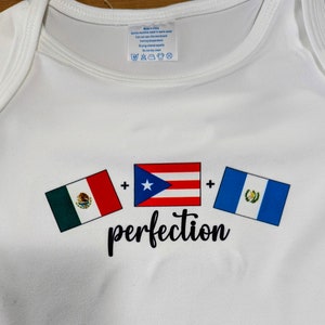 May include: White baby onesie with three flags printed on it. The flags are the Mexican flag, the Puerto Rican flag, and the Guatemalan flag. The text "perfection" is printed below the flags.