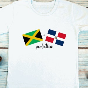 May include: White t-shirt with the flags of Jamaica and the Dominican Republic printed on it. The text " + perfection" is printed below the flags.