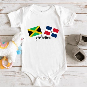 May include: White baby onesie with the Jamaican and Dominican Republic flags and the text "plus perfection".