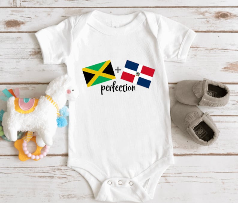 May include: White baby onesie with the Jamaican and Dominican Republic flags and the text "plus perfection".
