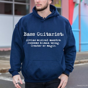 May include: A navy blue hooded sweatshirt with the text "Bass Guitarist: Divine musical maestro. Awesome human being. Creator of magic." printed in white on the front.