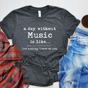 May include: A dark gray t-shirt with white text that reads "a day without Music is like... Just kidding. I have no idea."
