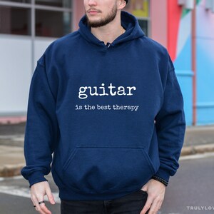 May include: A navy blue hoodie with a white graphic that says "guitar is the best therapy".