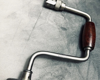Puede incluir: Una abrazadera de plata con un mango de madera y una manivela de metal. La abrazadera está etiquetada como "STEELANCE" y tiene un pequeño agujero en la manivela de metal.