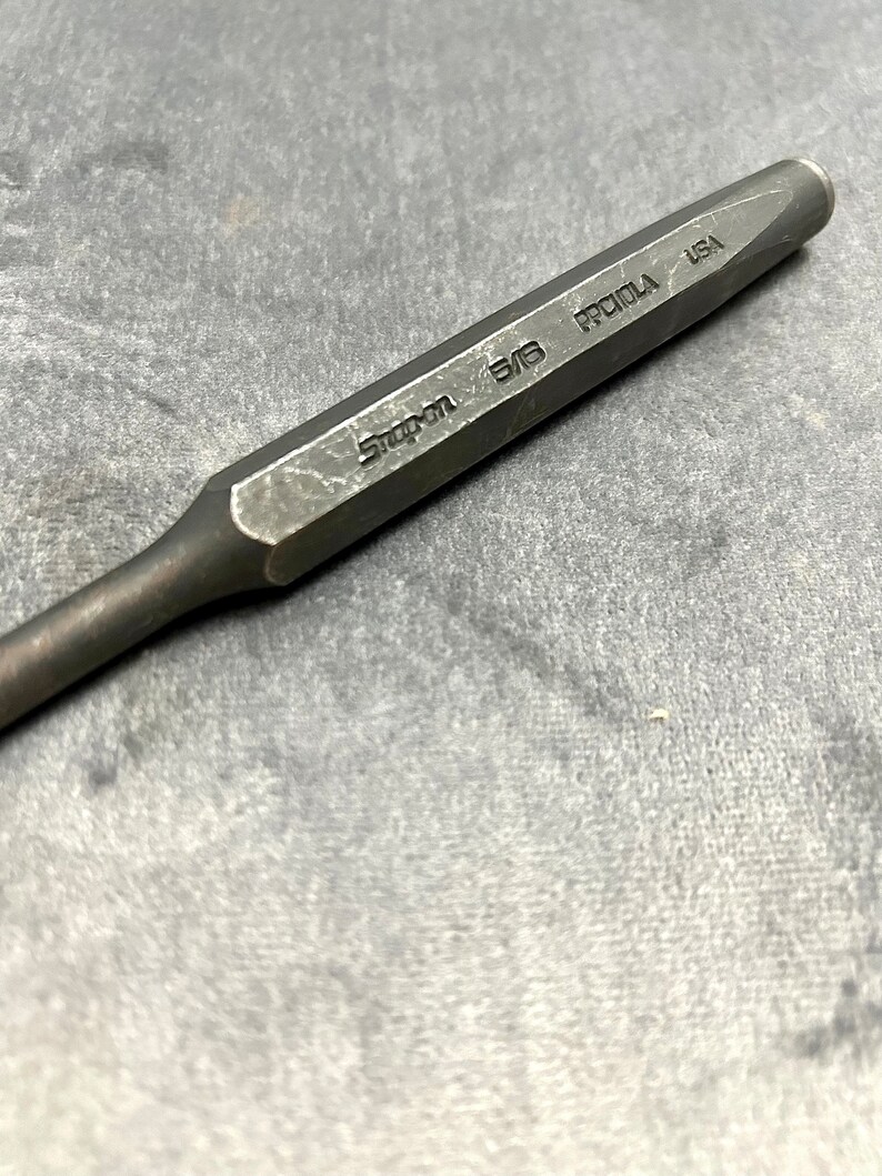 May include: A black metal punch with the text "Snap-on 5/8" and "PROTO USA" engraved on the side.