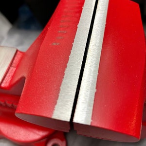 May include: A red metal vise with two silver jaws. The jaws are open and ready to clamp.