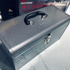 May include: A silver 18-inch Craftsman steel toolbox with a black handle and a silver latch. The toolbox has a textured finish and is made of metal.