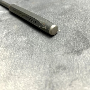 May include: A close-up of a gray metal punch tool with the text "WEAR HEAT SAFETY GOGGLES" engraved on the side.