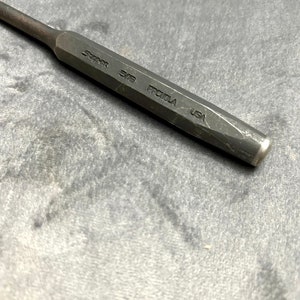 May include: A black metal punch with the text "Snap-on 3/8 PROTULA USA" engraved on the side.