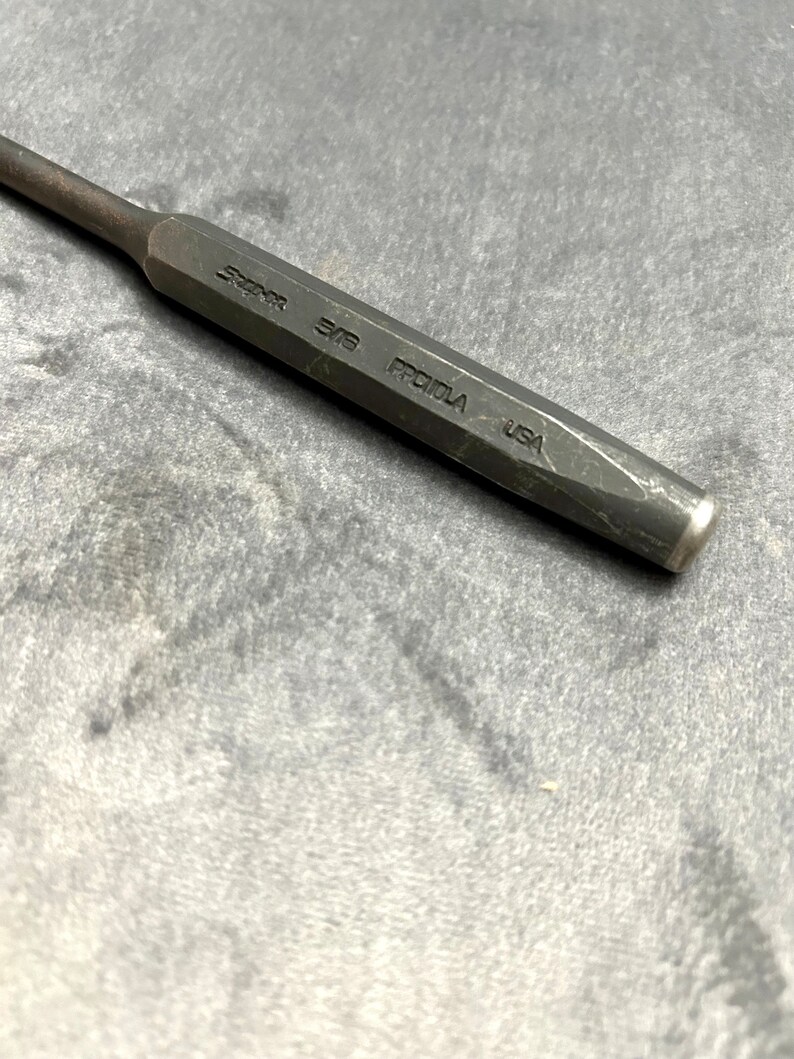 May include: A black metal punch with the text "Snap-on 3/8 PROTULA USA" engraved on the side.