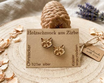 Könnte beinhalten: Holzohrringe in Fuchskopf-Form auf einer Karte aus Kraftpapier. Auf der Karte steht "Holzschmuck aus Zirbe" und "925er silber". Im Hintergrund ein Tannenzapfen und ein Lavendelzweig. Ein kleines Etikett mit "Handmade with Love".