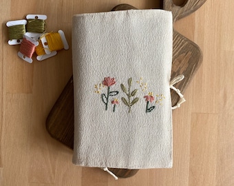 Handbroderat bokomslag i linne med blomsterträdgård, beige