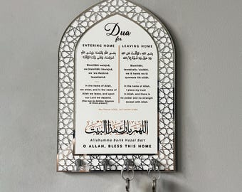 May include: A silver key holder with a white background and a decorative arch design. The key holder features Arabic text and the phrase "O Allah, Bless This Home".
