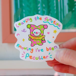 May include: A quirky sticker with a cartoon jester in a pink and green polka-dot costume, carrying a pink purse. The text on the sticker reads "Leaving the function, Knowing I've been Peculiar" in various colours. Stars and hearts decorate the design.