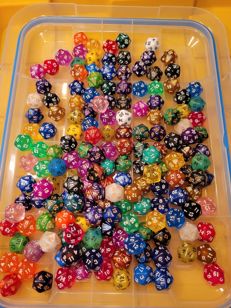 Op de afbeelding: Een verzameling kleurrijke polyhedrale dobbelstenen in een doorzichtige plastic organizer. De dobbelstenen zijn in verschillende kleuren, waaronder rood, blauw, groen, geel en paars. Elke dobbelsteen heeft witte of gouden cijfers. Voor bordspellen.