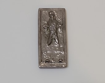 Op de afbeelding: Een zilveren metalen Han Solo carbonite-vriesframe. Het frame is rechthoekig en heeft een reliëfbeeld van Han Solo bevroren in carbonite.