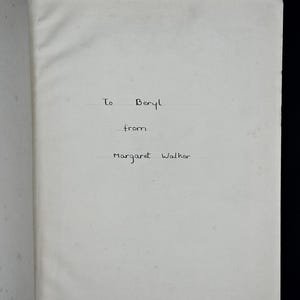 May include: An open book page with handwritten text. The text reads "To Beryl from Margaret Walker" in black ink. The paper is off-white and slightly textured, with a visible crease.