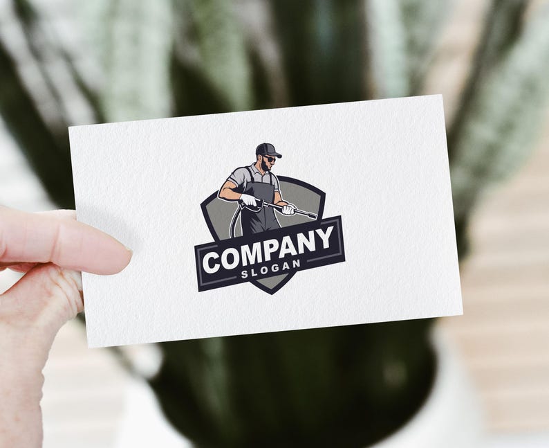 Pode incluir: Um design de logotipo com uma ilustra&ccedil;&atilde;o de desenho animado de uma pessoa usando um bon&eacute; e segurando uma lavadora de alta press&atilde;o. O logotipo est&aacute; sobre um escudo cinza com o texto "COMPANY" e "SLOGAN" abaixo.