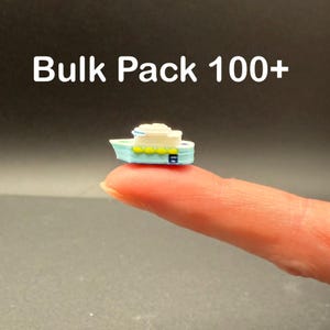 May include: A miniature light blue and white boat figurine with yellow accents, featuring the text Bulk Pack 100+ displayed above it. The small vessel has a multi-level structure and is shown in a side profile view against a dark background.